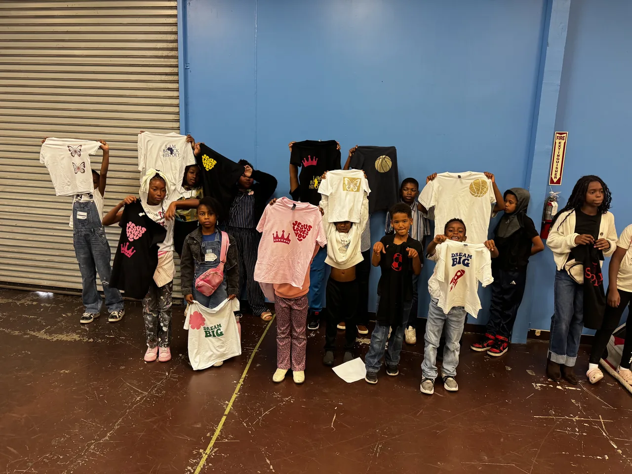 Students at SPARK Sunday hold up custom shirts with butterflies, crowns, basketballs and their own chosen designs.